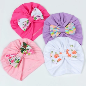 Détail d'un lot de quatre bonnets en coton pour bébé avec nœuds floraux colorés