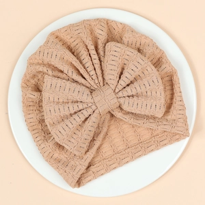 Gros plan détaillé d'un bonnet turban beige pour nouveau-né avec un grand nœud et texture