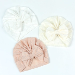 Detailed flat lay of three baby lace turbans in white, beige, and pink with large bows