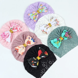 Flat lay of six breathable baby turban hats with large bows in various colors and patterns