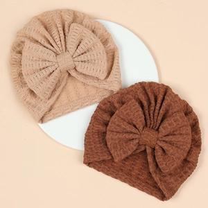 Détail de turbans gaufrés pour nouveau-né avec grands nœuds en beige et marron