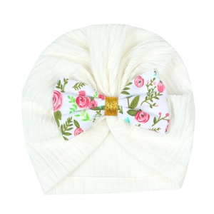 Detail of cream ribbed baby turban with floral bow and glitter gold center decoration