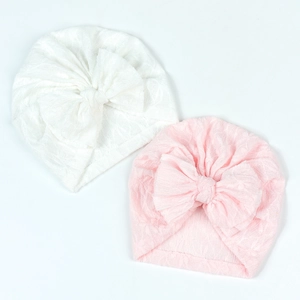 Close-up of white and pink infant turban hats with textured fabric and large bows
