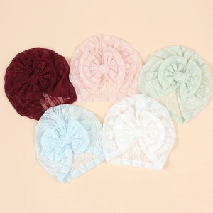 Flat lay view of newborn lace turban hats in five colors with large bow accents