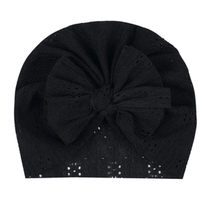 Détail du bonnet turban bébé en dentelle noire ajourée avec un grand nœud décoratif