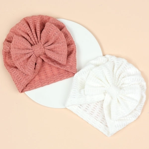 Détail des bonnets pour bébé en rose corail et blanc avec texture en maille gaufrée