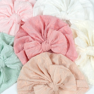Detailed view of six colors of baby turban hats with large bows and lace texture