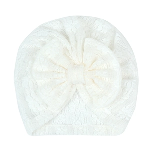 Close-up of white newborn turban hat with delicate lace texture and large bow detail