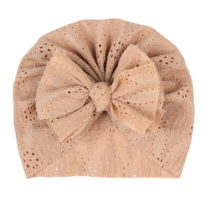 Détail de la texture dentelle respirante et du grand nœud sur un turban beige pour bébé