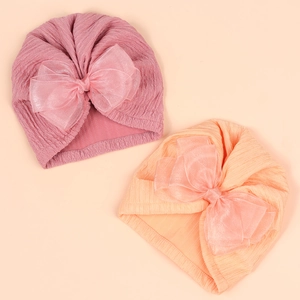 Detail view of pink and orange baby turban hats with large organza bow and ribbed texture