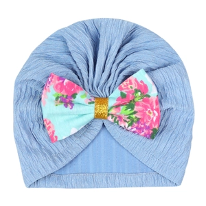 Detailed knit texture of light blue baby turban with a floral bow and gold glitter center