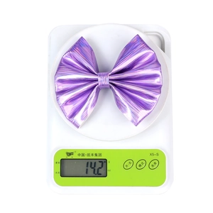 Macro shot showing purple holographic bow clip weighing 14.2g on a digital scale