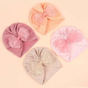 Infant ribbed knit turban hats with double mesh bows in four pastel colors on soft background