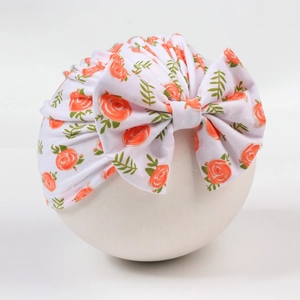 Detail einer Baby-Turbanmütze mit orangefarbenen Rosenmustern und großer Schleife