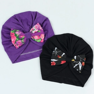 Détail de bonnets pour bébé avec grands nœuds à fleurs en violet et noir
