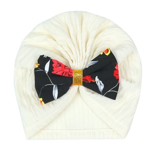 Detail of baby turban hat in cream ribbed fabric with a floral print bow decoration
