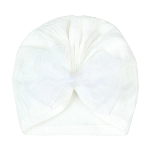 Detail of white baby turban hat with a large elegant organza bow on ribbed knit fabric