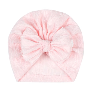 Detail view of pink baby turban hat with large bow and textured jacquard fabric pattern