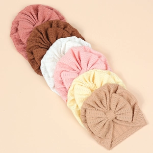 Lot de six bonnets bébé en tricot gaufré avec grands nœuds aux tons terreux doux
