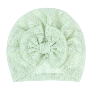Detail of light green breathable lace newborn hat featuring a delicate jacquard bow design