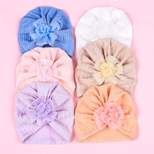 Flat lay of baby turban hats with organza flowers in six various soft colors