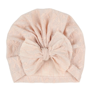 Close-up of pink infant turban hat showing intricate lace texture and a large bow