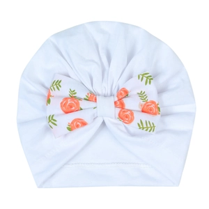 Détail du bonnet turban pour bébé en tricot blanc avec un grand nœud à imprimé floral rose