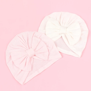Detail of breathable mesh baby hats with oversized bows in pink and cream white colors