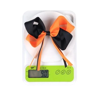 Gros plan d'un nœud en ruban d'Halloween sur une balance montrant un poids de 9,0 g