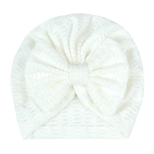 Détail du bonnet turban blanc pour nouveau-né avec grand nœud et tissu jacquard texturé