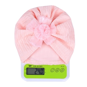 Detail showing pink baby turban hat with tulle flower weighing 24g on a scale