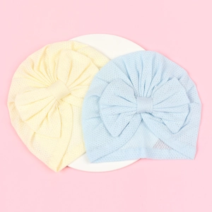 Detail view of two breathable mesh baby turban hats with large decorative bow knots