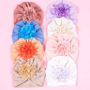 Flat lay of eight baby turban hats in pastel colors with golden dotted floral details