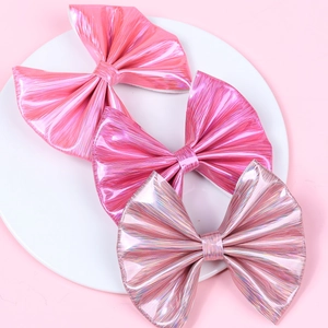 Three metallic pink leather bow hair clips in a white ceramic dish for girls