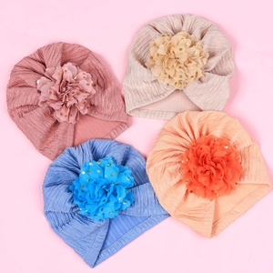 Detail view of four infant turban hats with pleated fabric and gold-dotted mesh flowers