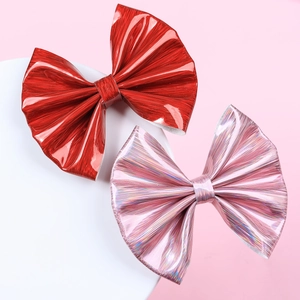 Detail of red and pink glossy leather bow hair clips with textured metallic finish