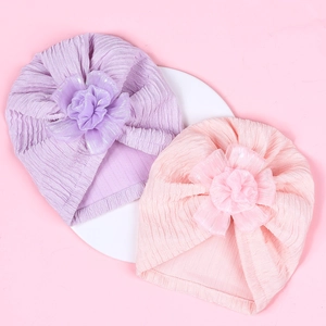 Detail view of baby turban hats with large floral accents and subtle silver glitter petals
