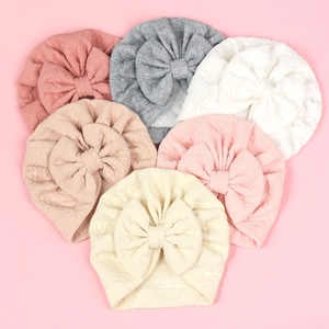 Flat lay of six baby waffle knit bow turbans arranged in a heart shape on a pink background