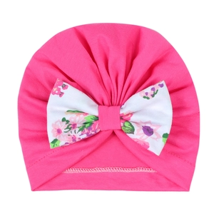 Détail du bonnet turban rose pour bébé avec un grand nœud décoratif à imprimé floral