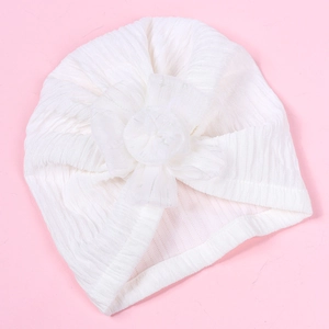 Detail of white baby turban featuring a large layered mesh flower and ribbed knit fabric