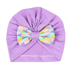 Détail d'un bonnet turban violet pour bébé en coton avec un nœud aux motifs géométriques