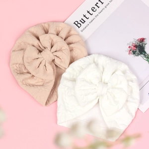 Detailed macro view of beige and white baby waffle knit beanies with large bows