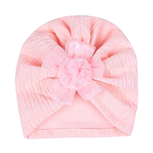 Detailed shot of pink baby turban hat with large mesh flower and vertical ribbed knit texture