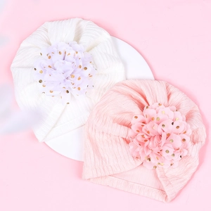 Detail of baby turban hats with ribbed knit texture and gold foil dot flower ornaments