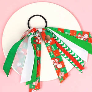 Détail de chouchou de Noël avec rubans à motifs Père Noël et rennes sur plateau blanc