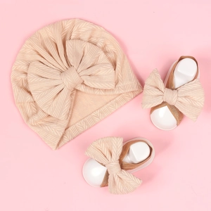 Detail of baby turban and bow sandals set in apricot pink ribbed knit fabric