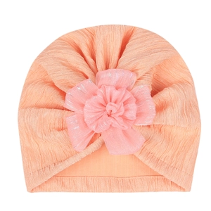 Detail of coral pink baby turban hat featuring a large 3D tulle flower and pleated texture