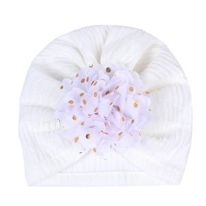 Close-up of white baby turban hat with large gold-spotted tulle flower detail