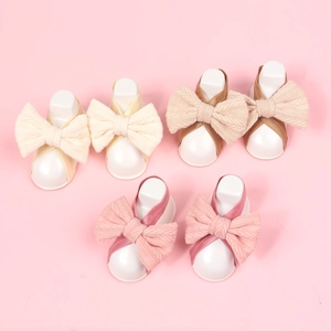 Detail of soft knit baby headbands with large bows in three pastel colors set on pink
