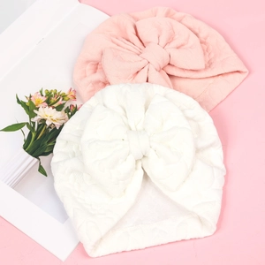 Close-up of pink and white quilted baby turbans with large bows and diamond textures